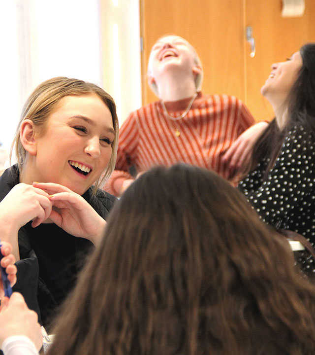 Unga tjejer skrattar i ett klassrum. 