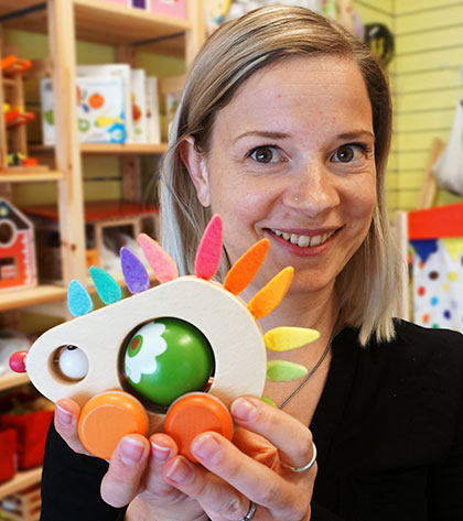 En person håller en färgglad leksak i händerna och tittar leende in i kameran