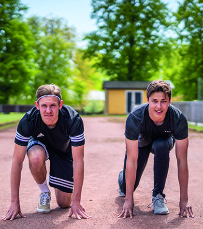 Två unga killar står i startposition på en löparbana