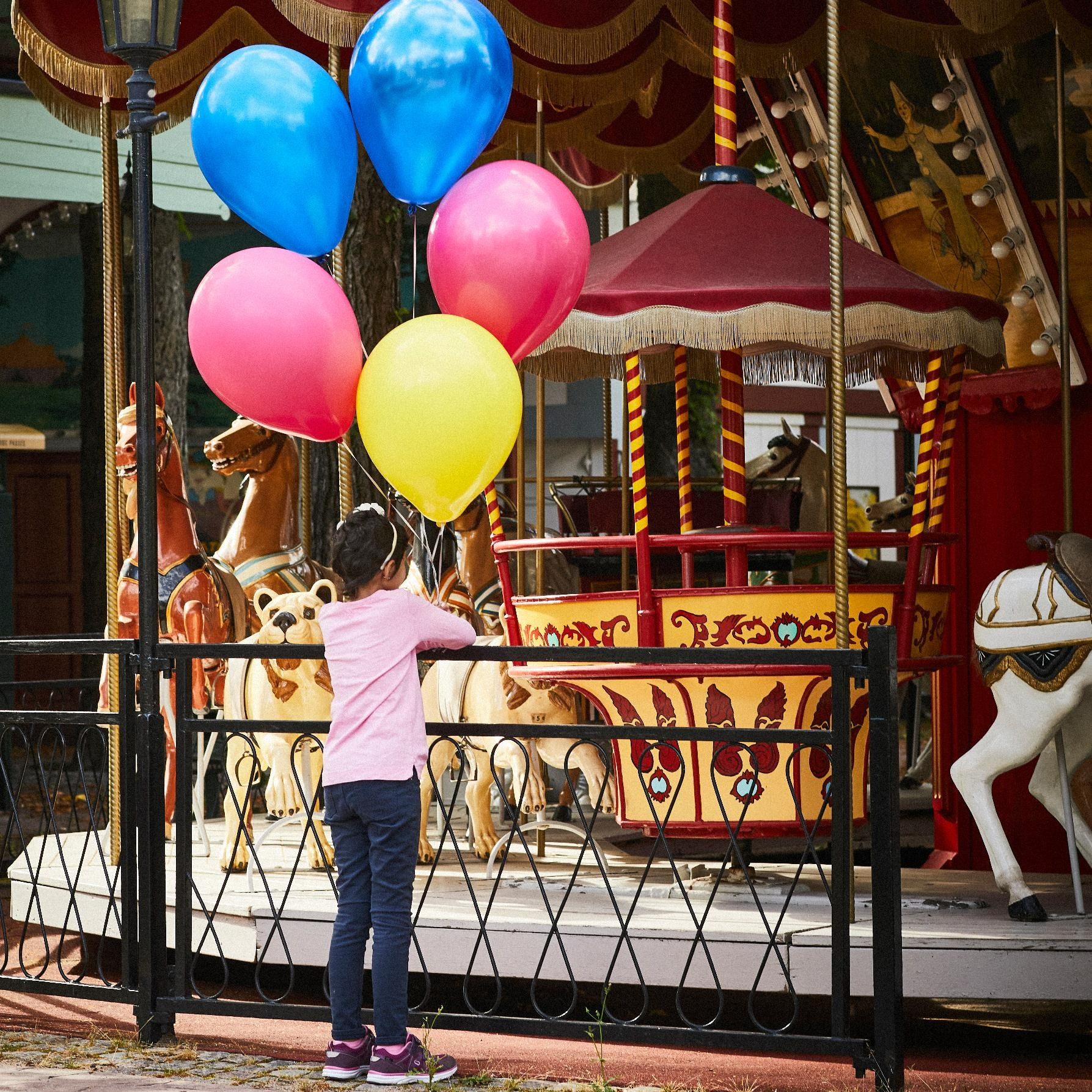 Min stora dag. Flicka med ballonger framför en karusell på tivoli. fotograf Magnus Ragnvid