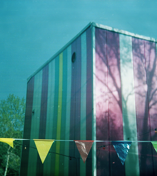 En byggnad syns i bakgrunden och framför hänger ett band med vimplar i olika färger.