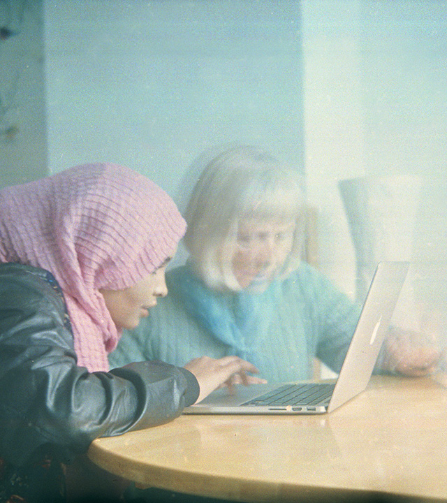 En ung  och en äldre kvinna sitter bredvid varandra framför en dator